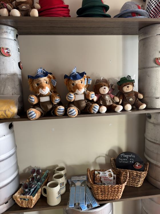 Gift shop shelf with a basket of Krush Brau magnets and a chalk sign reading Magnets Square $4, Wiener $6